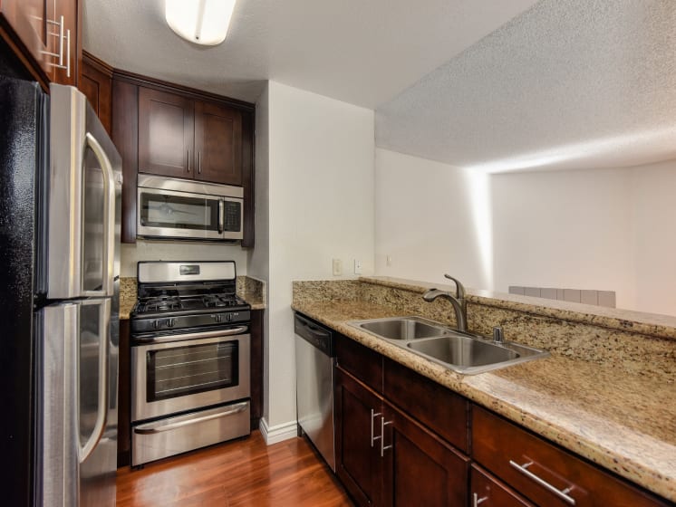Kitchen with Quartz Granite Countertops, Stainless Steel Refrigerator, Oven, Microwave, And Wood Cabinets